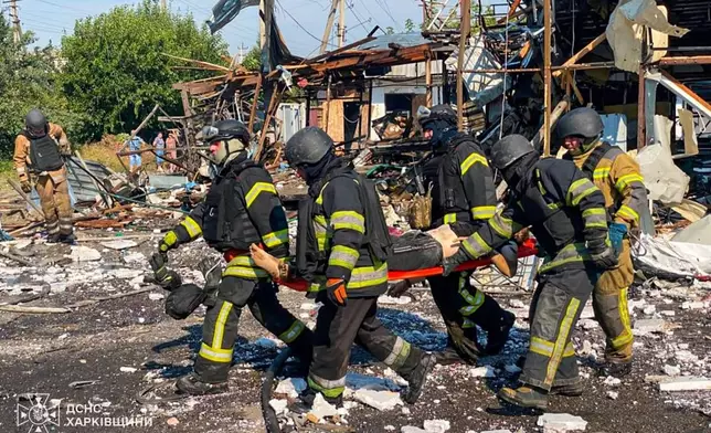 In this photo, provided by the Ukrainian Emergency Service, rescuers carry a body that they removed from under the rubble of a private house following a Russian air attack in Pechenihy, Kharkiv region, Ukraine, Tuesday, Aug. 18, 2026. (Ukrainian Emergency Service via AP)