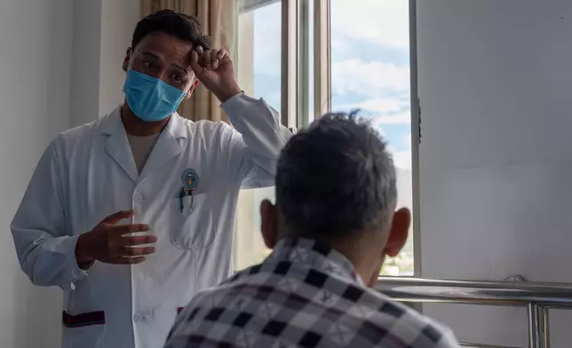 Gama, a physician, describes the therapy for a Tibetan man, right, in a ward of the Xizang Autonomous Region Hospital of Tibetan Medicine in Lhasa, in western China's Tibet Autonomous Region on Wednesday, July 22, 2026 as seen during a government organized visit for foreign journalists. (AP Photo/Ng Han Guan)
