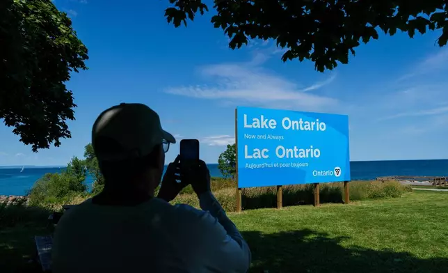A person takes a picture of the newly unveiled sign for Lake Ontario at Fifty Point Conservation Area in Grimsby, Ontario, Canada, on Saturday, Aug. 29, 2026. (Keito Newman/The Canadian Press via AP)