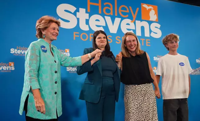 Former Sen. Debbie Stabenow, left, Rep. Haley Stevens, D-Mich., a candidate in the Democratic primary for U.S. Senate in Michigan, center left, and Rep. Hillary Scholten, D-Mich., hold hands on stage during a primary election night event Wednesday, Aug. 5, 2026, in Detroit. (AP Photo/Paul Sancya)