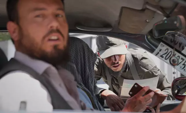 A Taliban security officer checks a driver's identification at a checkpoint ahead of celebrations marking the fifth anniversary of the U.S. withdrawal from Afghanistan and the start of Taliban rule, in Kabul, Afghanistan, Thursday, Aug. 13, 2026. (AP Photo/Siddiqullah Alizai)