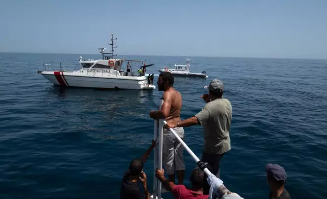 Boats of fishermen and Tunisian national guard approach a drowned body during a search operation after a boat carrying migrants capsized off the country's southeastern coast, near Zarzis, Tunisia, Sunday, Aug. 23, 2026. (AP Photo/Bassem Aouini)