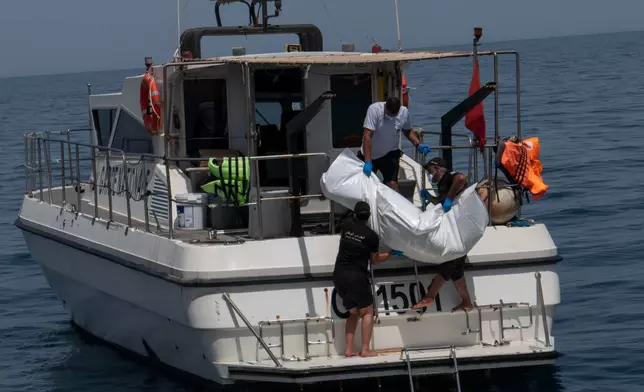 Tunisian national guard members recover a drowned body during a search operation after a boat carrying migrants capsized off the country's southeastern coast, near Zarzis, Tunisia, Sunday, Aug. 23, 2026. (AP Photo/Bassem Aouini)