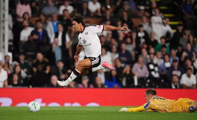 Fulham's Gonzalo Garcia, left, gets past the AFC Wimbledon goalkeeper Nathan Bishop to score their third goal of the game during the League Cup soccer match between Fulham and AFC Wimbledon in London, Thursday, Aug. 27, 2026. (John Walton/PA via AP)
