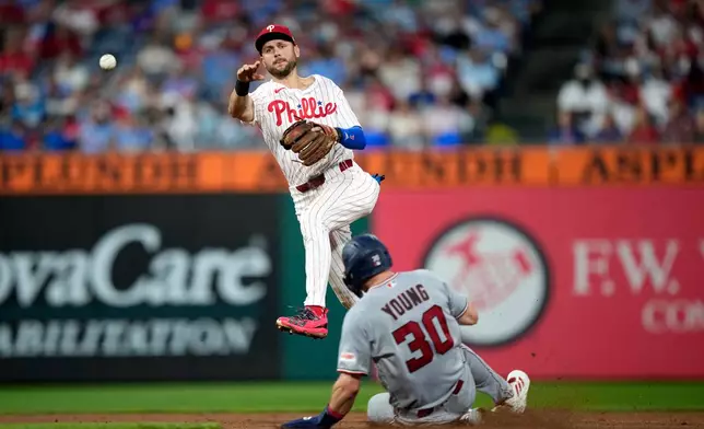 Philadelphia Phillies shortstop Trea Turner, left, throws to first after forcing out Washington Nationals' Jacob Young at second on a double play hit into by CJ Abrams during the fifth inning of a baseball game Wednesday, Aug. 5, 2026, in Philadelphia. (AP Photo/Matt Slocum)