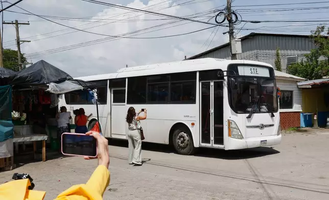Journalists take images of a bus transporting migrants deported from the United States following their arrival at the Ramón Villeda Morales Airport in San Pedro Sula, Honduras, Thursday, Aug. 20, 2026. (AP Photo/Delmer Martinez)