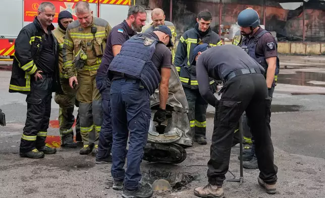 Firefighters examine a fragment of a Russian missile after air strikes at a food warehouse in Kyiv, Ukraine, Wednesday, Aug. 5, 2026. (AP Photo/Efrem Lukatsky)