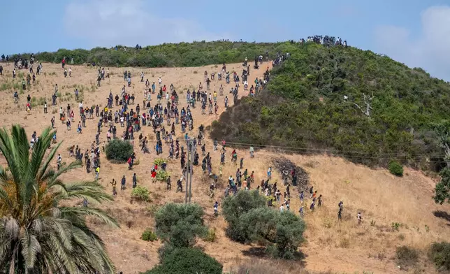 Migrants gather on a hill as they attempt crossing from the border town of Fnideq to the Spanish enclave of Ceuta, Saturday, Aug. 15, 2026. (AP Photo)