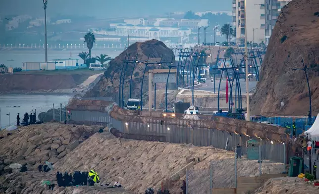 Morocco security forces, bottom left, patrol the Spanish-Moroccan border seen from the Spanish enclave of Ceuta, Saturday, Aug. 15, 2026. (AP Photo/Antonio Sempere)