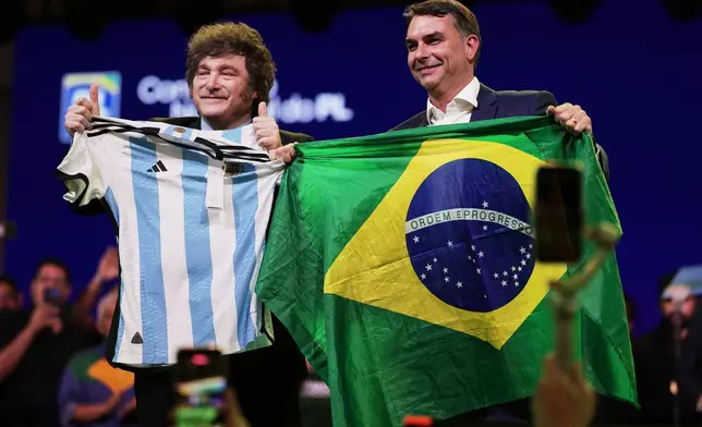 Brazilian Sen. Flavio Bolsonaro holds a Brazil national flag as Argentina's President Javier Milei holds an Argentina local selection jersey, during the Liberal Party convention where Bolsonaro was confirmed as the party's presidential candidate, in Sao Paulo, Saturday, July 25, 2026. (AP Photo/Ettore Chiereguini)