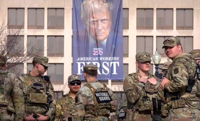 FILE - National Guard members gather near a large portrait of President Donald Trump on the Labor Department headquarters before the body of Metropolitan Police Department officer Terry Bennett is driven past the Capitol, Jan. 8, 2026, in Washington. (AP Photo/Mark Schiefelbein, File)