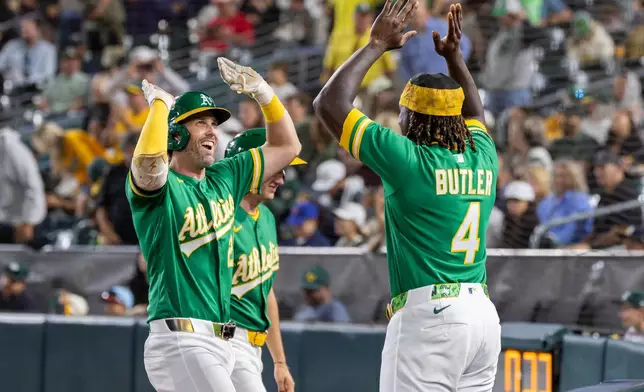 Athletics' Jeff McNeil, left, high-fives Lawrence Butler (4) after hitting a home run during the sixth inning of a baseball game against the Texas Rangers Friday, Aug. 14, 2026, in West Sacramento, Calif. (AP Photo/Sara Nevis)