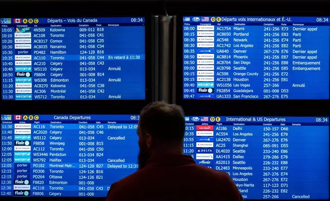 A traveller looks to an information board as WestJet flights are cancelled at Vancouver International Airport in Richmond, British Columbia, Sunday, Aug. 2, 2026. (Ethan Cairns/The Canadian Press via AP)