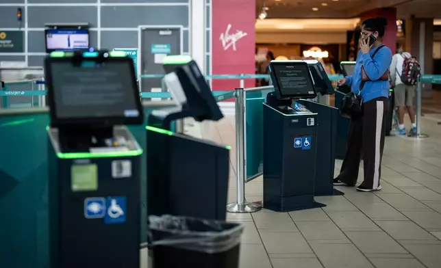 A traveller tries to check in for a cancelled WestJet flight at Vancouver International Airport in Richmond, British Columbia, Sunday, Aug. 2, 2026. (Ethan Cairns/The Canadian Press via AP)