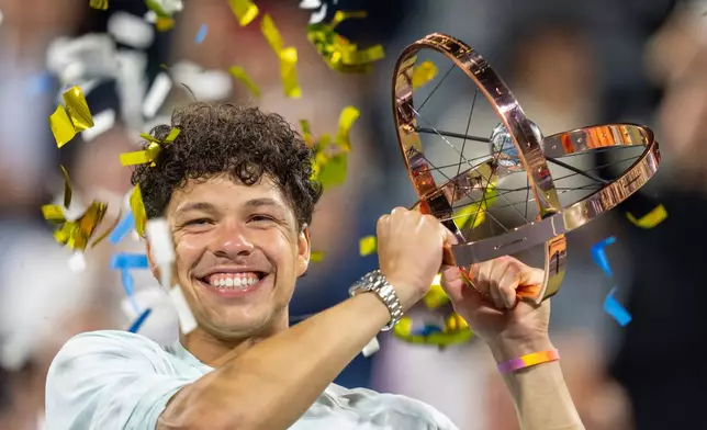 Ben Shelton of the United States hoists the trophy following his win over compatriot Brandon Nakashima during final tennis action at the National Bank Open in Montreal on Thursday, Aug. 13, 2026. (Christinne Muschi/The Canadian Press via AP)