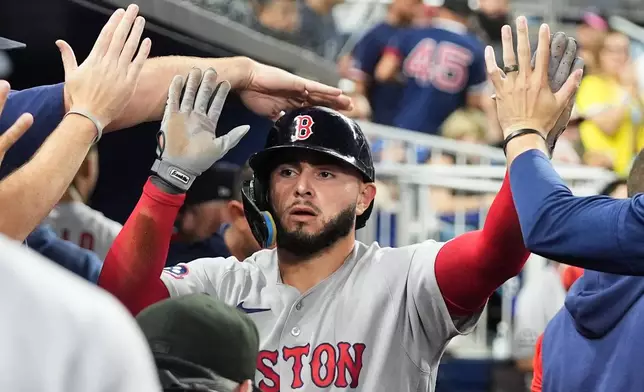 Boston Red Sox's Wilyer Abreu is congratulated in the dugout after scoring on a wild pitch thrown by Miami Marlins relief pitcher Josh Ekness during the eighth inning of a baseball game, Monday, Aug. 24, 2026, in Miami. (AP Photo/Lynne Sladky)