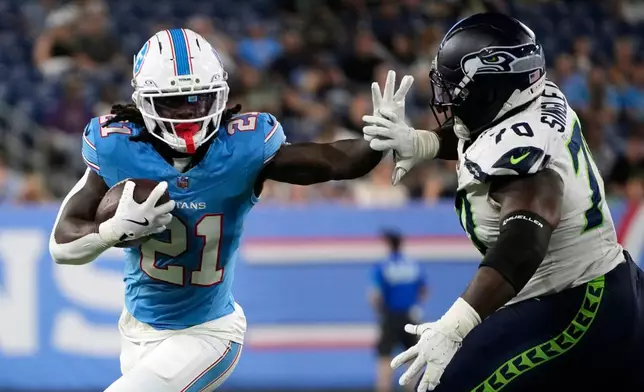 Tennessee Titans running back Dominic Richardson (21) runs from Seattle Seahawks defensive tackle J.R. Singleton (70) during the second half of a preseason NFL football game, Sunday, Aug. 23, 2026, in Nashville, Tenn. (AP Photo/George Walker IV)