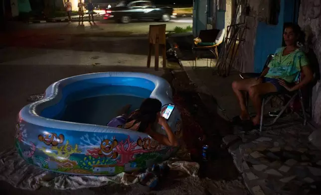 A girl cools off in a plastic pool in the street in Havana, Cuba, Tuesday, Aug. 4, 2026. (AP Photo/Ramon Espinosa)