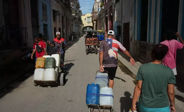 People carry water during a power outage in Havana, Cuba, Monday, Aug. 3, 2026. (AP Photo/Ramon Espinosa)
