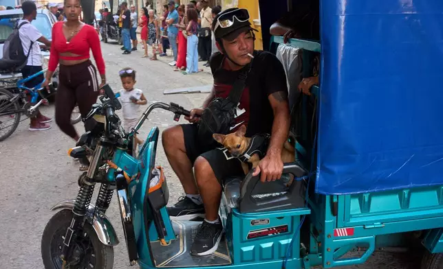 A man maneuvers his electric tricycle alongside his small dog in Havana, Cuba, Wednesday, July 29, 2026. (AP Photo/Ramon Espinosa)