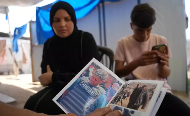 Family members of Palestinian journalist Hussam al-Masri, who worked as a freelance journalist for Reuters and was killed in an Israeli airstrike targeting the Nasser Hospital building in Khan Younis on Aug. 25, 2025, look at his photos in Khan Younis, southern Gaza Strip, Aug. 16, 2026. (AP Photo/Abdel Kareem Hana)