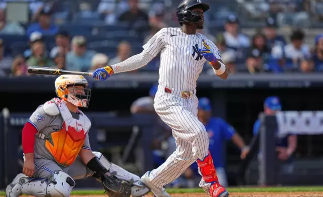 Toronto Blue Jays catcher Alejandro Kirk, left, watches as New York Yankees' Jazz Chisholm Jr. follows through on a single during the seventh inning of a baseball game Saturday, Aug. 22, 2026, in New York. (AP Photo/Frank Franklin II)