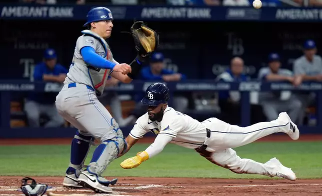 Tampa Bay Rays' Cedric Mullins, right, scores ahead of the throw to Toronto Blue Jays catcher Brandon Valenzuela on a bunt during the fourth inning of a baseball game Wednesday, Aug. 19, 2026, in St. Petersburg, Fla. (AP Photo/Chris O'Meara)