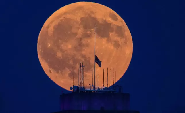 The full moon rises beyond the city hall in downtown Kansas City, Mo., before a lunar eclipse Thursday, Aug. 27, 2026. (AP Photo/Charlie Riedel)