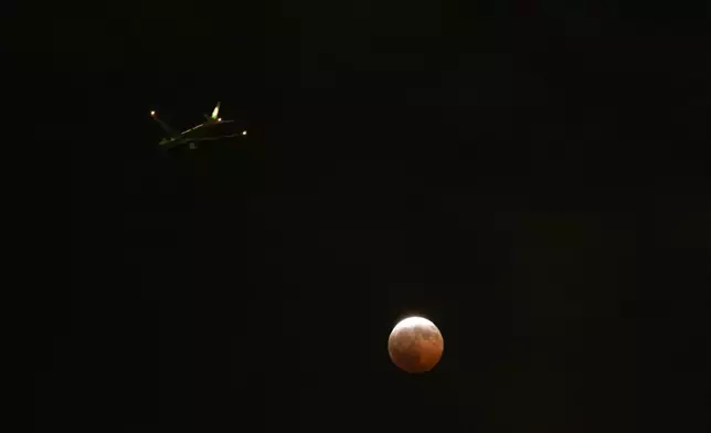 An airplane flies past a partial lunar eclipse in Los Angeles, Thursday, Aug. 27, 2026. (AP Photo/Jae C. Hong)