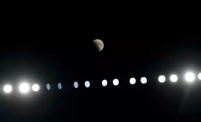 A partial lunar eclipse is seen above the stadium light during a pre-season NFL football game between the Cleveland Browns and the New England Patriots, Thursday, Aug. 27, 2026, in Cleveland. (AP Photo/Carolyn Kaster)