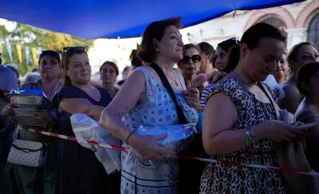 Pilgrims wait in line to have their Fanouropites, orange-flavored cakes, blessed at the Church of St. Fanourios in Athens, Wednesday, Aug. 26, 2026. (AP Photo/Thanassis Stavrakis)