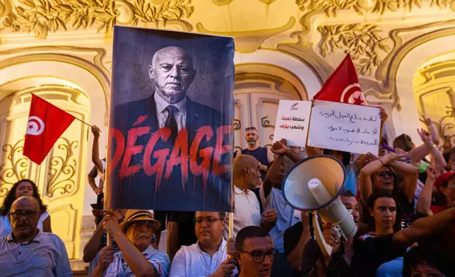 People take part in a protest against rising prices, declining purchasing power and shortages of basic goods in Tunis, Tunisia, Thursday, Aug. 20, 2026. Banner in French showing Preident Kais Saied reads "Leave". (AP Photo/Ons Abid)