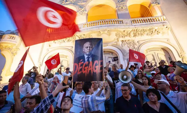 People take part in a protest against rising prices, declining purchasing power and shortages of basic goods in Tunis, Tunisia, Thursday, Aug. 20, 2026. Banner in French showing Preident Kais Saied reads "Leave". (AP Photo/Ons Abid)