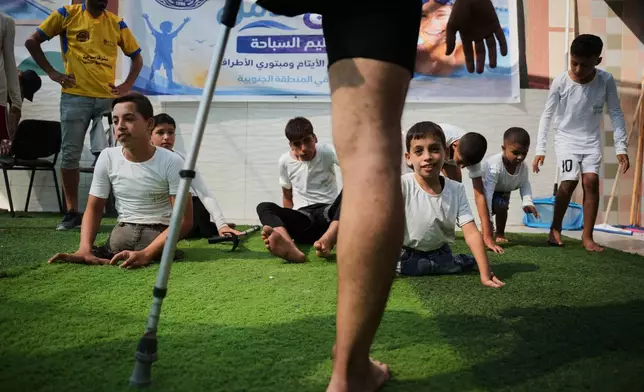 Coach Nour Qashqash warms up with children who lost limbs after being injured during the war between Israel and Hamas, during a swimming training session organized by the Heal Palestine organization at a pool in Khan Younis, Gaza Strip, Wednesday, Aug. 19, 2026. (AP Photo/Abdel Kareem Hana)