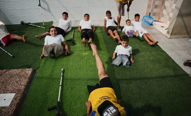 Coach Nour Qashqash warms up with children who lost their legs after being injured in the war between Israel and Hamas during a swimming training session organized by the Heal Palestine organization at a pool in Khan Younis, Gaza Strip, Wednesday, Aug. 19, 2026. (AP Photo/Abdel Kareem Hana)