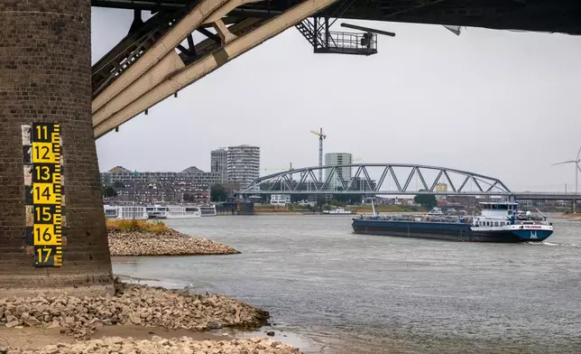 A barge passes under a bride on the Lek river near Beusichem, Netherlands, Thursday, July 30, 2026, due to drought conditions. (AP Photo/Patrick Post)