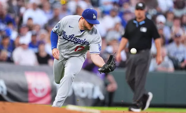 Los Angeles Dodgers third baseman Max Muncy tries to field a single off the bat of Colorado Rockies' Braxton Fulford in the second inning of a baseball game Tuesday, Aug. 18, 2026, in Denver. (AP Photo/David Zalubowski)
