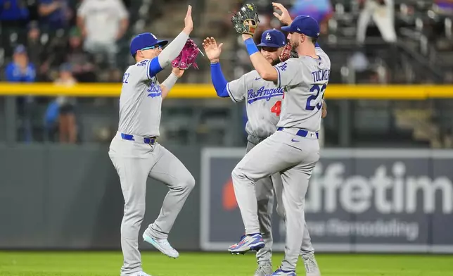 Los Angeles Dodgers left fielder Enrique Hern·ndez, left, celebrates with center fielder Andy Pages and right fielder Kyle Tucker, right, after defeating the Colorado Rockies in a baseball game Tuesday, Aug. 18, 2026, in Denver. (AP Photo/David Zalubowski)