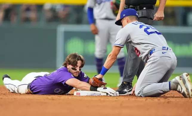Colorado Rockies' Connor Norby, left, slides safely into second base with an RBI double as Los Angeles Dodgers second baseman Tommy Edman applies a late tag in the third inning of a baseball game Tuesday, Aug. 18, 2026, in Denver. (AP Photo/David Zalubowski)
