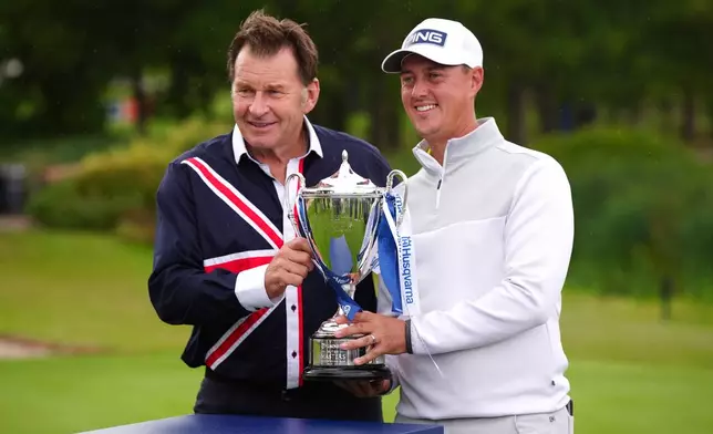 Joe Dean of England, right, receives the trophy from Nick Faldo on day four of the British Masters at The Belfry Hotel & Resort, Sutton Coldfield, England, Sunday Aug. 30, 2026. (Bradley Collyer/PA via AP)