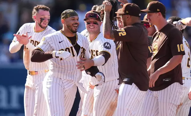 San Diego Padres' Luis Campusano, second from left, celebrates with teammates after hitting a walk off single to defeat the Brewers during the eleventh inning of a baseball game Wednesday, Aug. 12, 2026, in San Diego. (AP Photo/Gregory Bull)