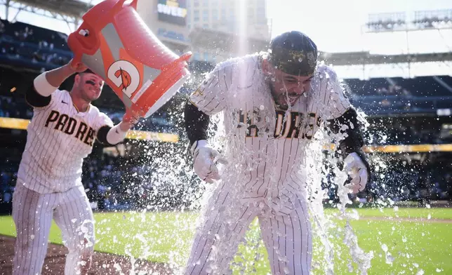San Diego Padres' Luis Campusano, right, is doused by teammate Ty France after Campusano hit a walk off single and. the Padres defeated the Milwaukee Brewers 4-3 in a baseball game Wednesday, Aug. 12, 2026, in San Diego. (AP Photo/Gregory Bull)