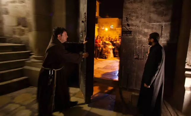 FILE - A priest closes the door to the Holy Sepulcher church for the night in Jerusalem on Thursday, May 17, 2012. (AP Photo/Dusan Vranic, File)