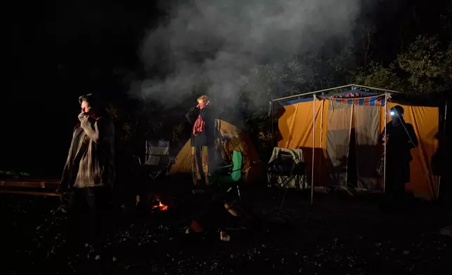 Land defenders gather on a logging road before dawn as a logging vehicle approaches the blockade near Port Renfrew, British Columbia, Thursday, May 28, 2026. (AP Photo/Annika Hammerschlag)