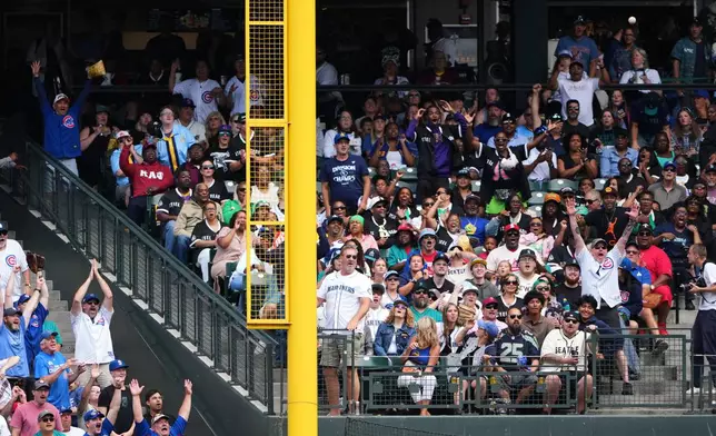 Fans react as the grand slam from Chicago Cubs' Ian Happ against the Seattle Mariners goes into the stands during the third inning of a baseball game, Sunday, Aug. 23, 2026, in Seattle. (AP Photo/Lindsey Wasson)