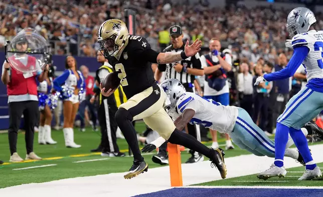 New Orleans Saints quarterback Spencer Rattler (2) scores a touchdown in front of Dallas Cowboys linebacker Isaiah Land (58) during the first half of a preseason NFL football game, in Arlington, Texas, Friday, Aug. 28, 2026. (AP Photo/Tony Gutierrez)