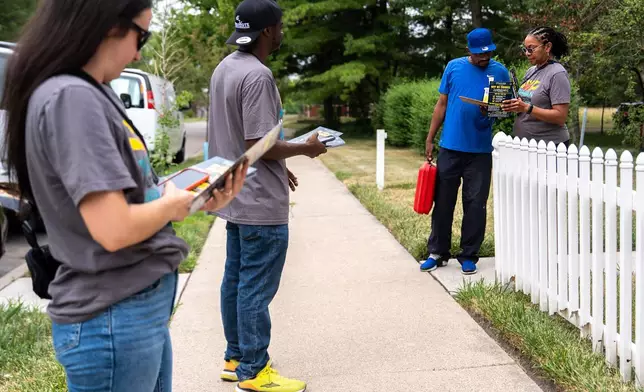 Darci McConnell, communications director, right, talks to a voter as Madison Steigerwald, canvas lead, left, Kenneth Brooks, canvasser, second from right, watch, while canvassing with Michigan United Action for candidates including Abdul El-Sayed, a progressive candidate in the Democratic primary for U.S. Senate in Michigan, Saturday, Aug. 1, 2026, in Detroit. (AP Photo/Julia Demaree Nikhinson)