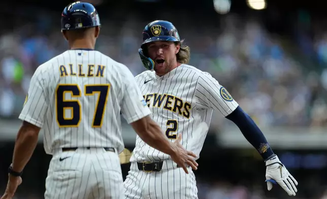 Milwaukee Brewers' Brice Turang (2) celebrates with first base coach Spencer Allen (67) after hitting a two-run single during the fourth inning of a baseball game against the Minnesota Twins, Saturday, Aug. 8, 2026, in Milwaukee. (AP Photo/Aaron Gash)