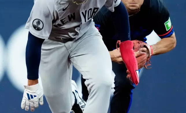 New York Yankees' George Lombard Jr., front, gets caught in a rundown as Toronto Blue Jays shortstop Andrés Giménez, back, pursues during the first inning of a baseball game in Toronto, Friday, Aug. 14, 2026. (Chris Young/The Canadian Press via AP)