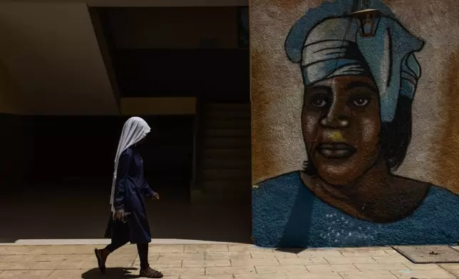 A student walks past a wall painting of Mariama Ba at the Mariama Ba school in Goree Island, Senegal, Thursday, March 12, 2026. (AP Photo/Caitlin Kelly)